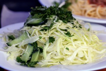 fresh salad of white cabbage and green cucumbers on a plate