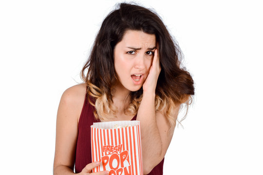 Young woman watching a scary movie and eating popcorn.