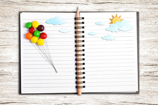 Put multicolor candy (draw line for balloon) and paper craft put on note book on wood background., With zine culture. - Powered by Adobe