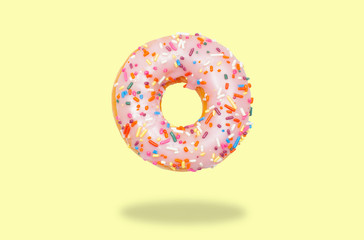 Pink donut on on pastel yellow background.