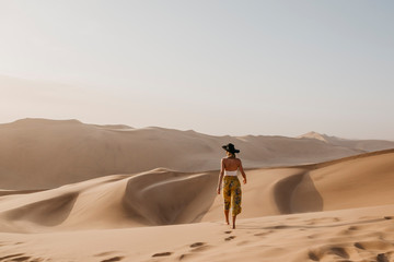 Namibia, Namib, back view of woman walking barefoot on desert dune