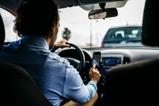 Businessman driving car using cell phone as navigation system