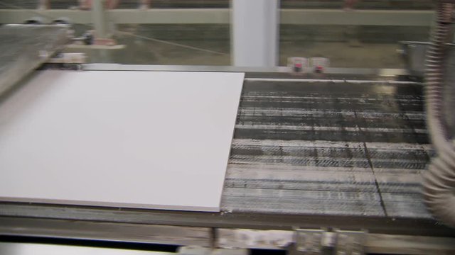 white plates are moving over transporting belt of conveyor in working hangar of plant