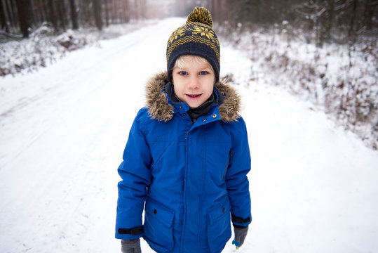 Portrait of little boy enjoying walk in winter forest