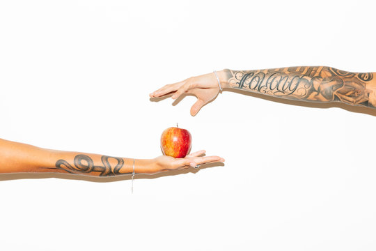 Woman's hand offering an apple to a man