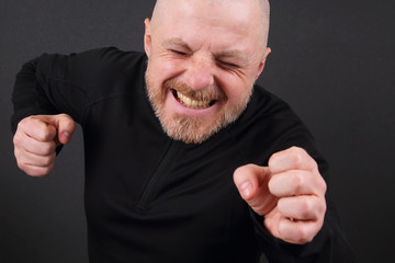 Emotional bearded man with clenched hands in pursuit of victory
