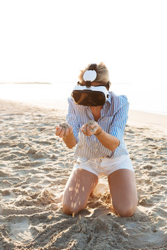 Thailand, woman using virtual reality glasses on the beach in the morning light