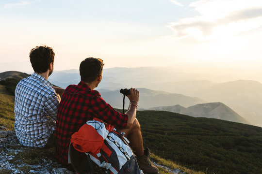Italy, Monte Nerone, two hikers on top of a mountain enjoying the view at sunset