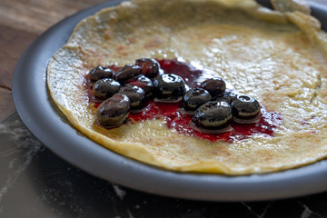 blueberry sauce on a crepe / pancake, on a black plate