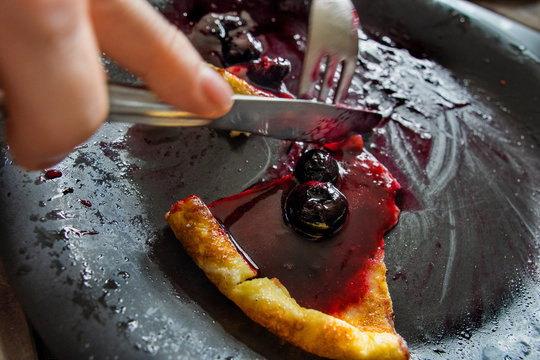eating a pancake with blueberry sauce