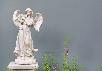 Beautiful angel statue against gray wall background.