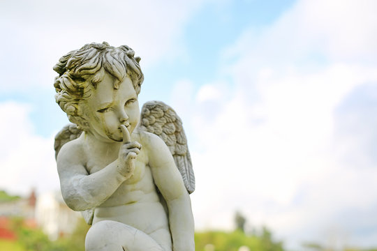 Cupid sculpture in summer garden outdoor.