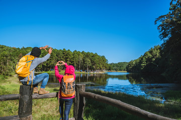 Couples travelers with backpack happy to relax on a holiday, travelers Pang-Ung park travel,Travel to visit nature landscape the beautiful at lake, at Mae-hong-son, in Thailand.