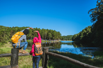 Couples travelers with backpack happy to relax on a holiday, travelers Pang-Ung park travel,Travel to visit nature landscape the beautiful at lake, at Mae-hong-son, in Thailand.