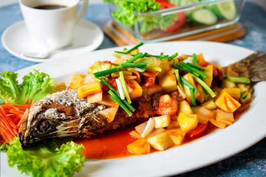 sweet and sour  Fried fish with mango on blue table whit White Coffee Cup and  Vegetable 