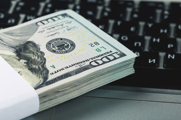 Closeup view of one hundred dollar banknotes lying on the laptop keyboard