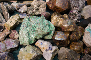 Large piece of raw malachite between other stone fragments at the exhibition of minerals