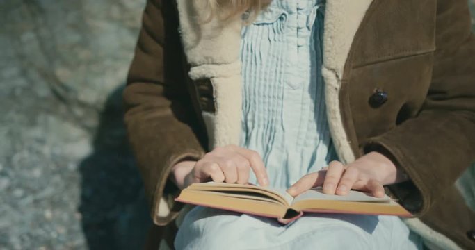 Woman in sheepskin coat reading outdoors