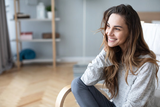 Happy Woman Posing Sitting On A Sofa In The Living Room At Home.