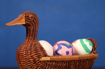 Easter color eggs in the Duck basket. wicker basket of straw. festive meal on a dark wooden table.