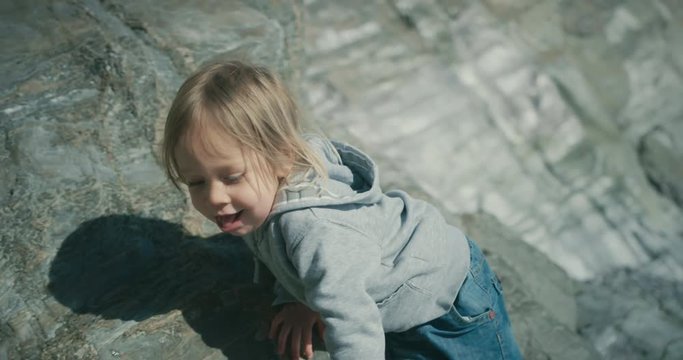 Little toddler climbing on a rock