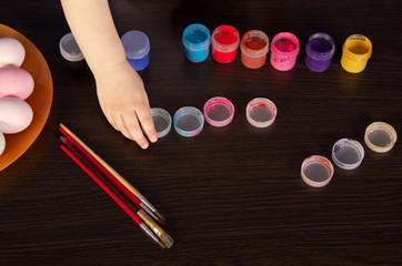 a child paints Easter eggs. hand, paintbrush and paint on the table. preparation for Easter.