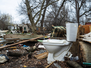 The toilet bowl left on a dump. A dump among the destroyed buildings