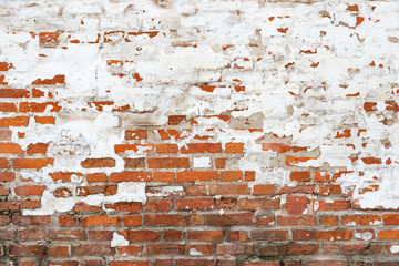 The texture of the old brick wall painted white with peeling paint
