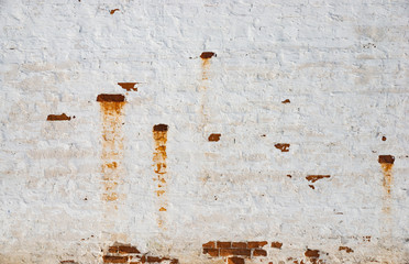 The texture of the old brick wall painted white with peeling paint