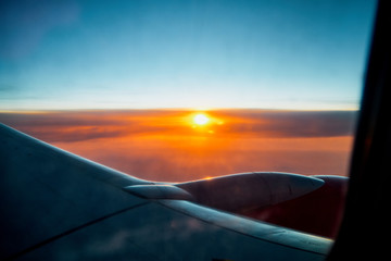 Fototapeta na wymiar View of airplane wing, sunset and clouds through window of plane