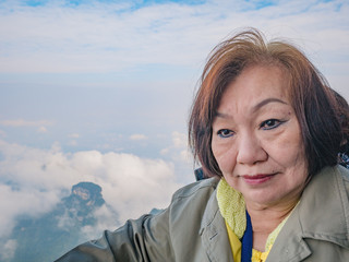 Portrait photo of beautiful asian senior women with beautiful view on Tianmen mountain and clear Sky in zhangjiajie city China.Tianmen mountain the travel destination of Hunan zhangjiajie city China