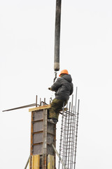 Working on the scaffolding pours concrete foundations at a height of