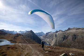 Paraglider Pilot takes off with his paraglider to take off and fly into the valley in the Swiss...