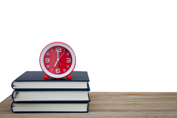 Old book and clock on wooden table on white background,soft focus.