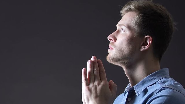 Light falling on man praying faithfully to god, belief in changes for better