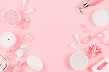 Different cosmetic products and accessories in pink and silver color as decorative border on soft light pink background, copy space, top view.