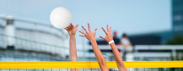 Hands playing beach volleyball