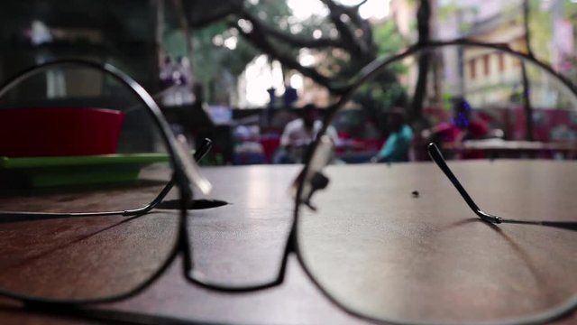 eye glass on coffee table with people on background