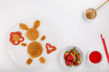 Funny bunny pancakes  in white plate on white background. Creative breakfast for kids, Easter pancakes. Top view, copy space.
