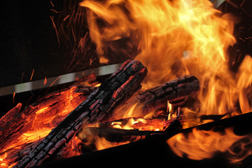 Fototapeta premium A shot of burning firewood in the fireplace. Close-up. Burning wood for a barbecue. Smoke and sparks. Fire background.