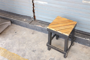 Wooden stool in front of metal door.