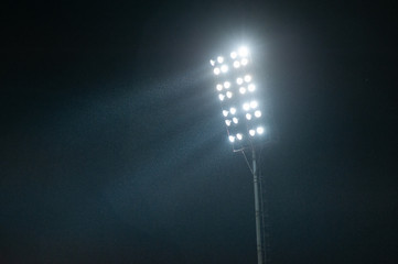 Stadium light against night sky. High mast of spot light. Light lines