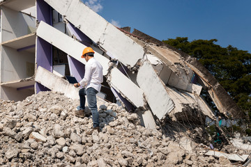 Engineer holding laptop is checking for destruction, demolishing building.