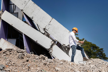 Engineer holding laptop is checking for destruction, demolishing building.