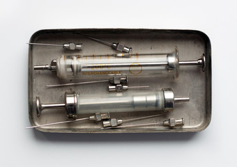 An old glass syringes and a metal box-sterilizer.