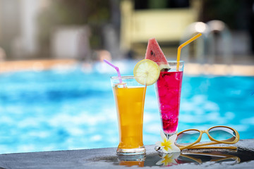 Summer holiday tropical concept. Fresh  orange juice and watermelon juice on border of a swimming pool.