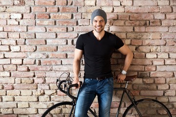 Fototapeta na wymiar Young athletic man with bicycle at brick wall