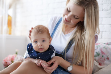 Young mother holding her newborn child.Woman and new born boy relax in a white bedroom.A young mother gently holds her newborn son in her arms.Family at home.Young mother playing whith her newborn son