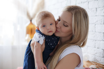 Young mother holding her newborn child.Woman and new born boy relax in a white bedroom.A young mother gently holds her newborn son in her arms.Family at home.Young mother playing whith her newborn son