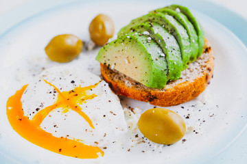 Healthy food concept: toast with avocado, green olives and poached egg